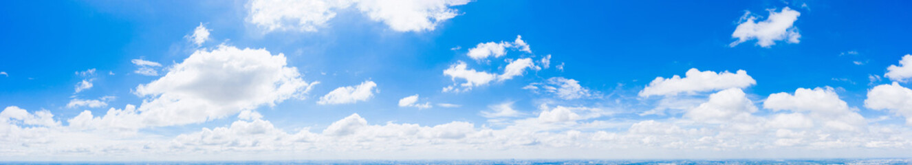 Panoramic view of bright blue sky with fluffy white clouds scattered across, symbolizing fresh air and peaceful nature, perfect for backgrounds or environmental design.