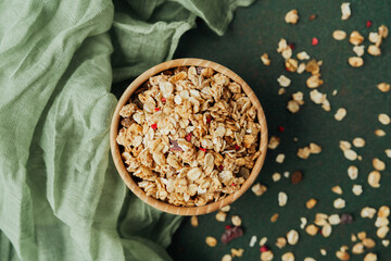 Top view granola bowl with scattered oats and green textile