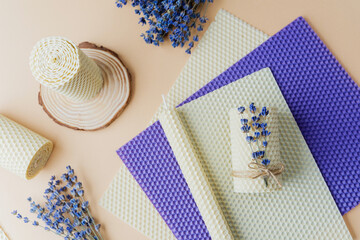 Beeswax candle on wood base with lavender on beige background