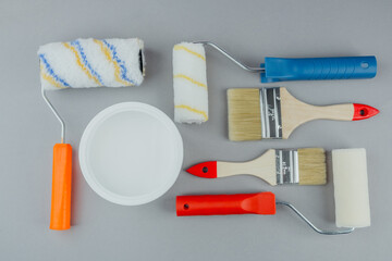 Set of paint tools with colorful rollers, brushes and bucket of white paint for DIY renovation and...