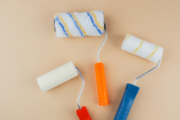 Closeup of colorful paint rollers on beige background for painting textures and DIY concept