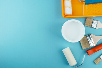 Flat lay of painting tools and bucket on cyan background for creative decorating and DIY renovation...