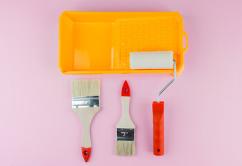 Painting set with tray, roller and brushes on pink background for DIY tools and interior work...