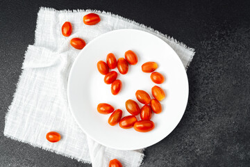 Cherry tomatoes arranged on a white plate on a dark textured surface
