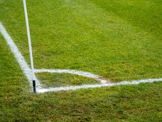 A close-up captures a white corner flag and lines on a vibrant green soccer field, ready for play.