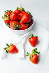 Fresh strawberries arranged in a bowl on a white cloth in a bright setting