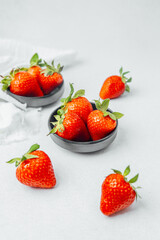 Bright red strawberries are neatly placed in bowls on a clean white surface