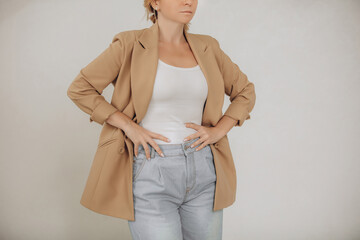 Elements of clothing, a businesswoman in a beige jacket, T-shirt and jeans on a white background