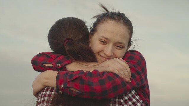 girl hugs her friend outdoors nature, happy family, daughter smiles on mom's shoulder, trust relationships of people, kindness and support with good smile emotions, sincere tenderness day of gratitude