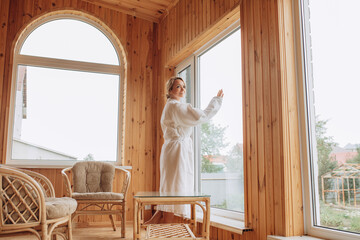 A young adult woman in a bathrobe on the veranda in the morning