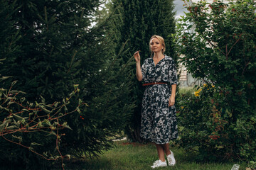A young adult woman walks in the park among the fir trees