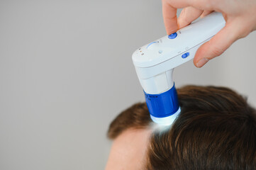 A trichologist examines the hair of a man who begins alopecia. Consultation with a dermatologist....