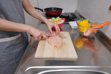 料理をする女性の手元のクローズアップ（鶏肉を切る）