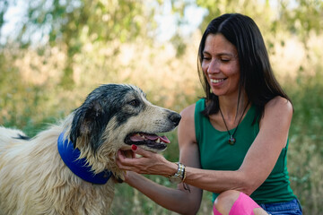 Dog owner petting her wet dog outdoors.