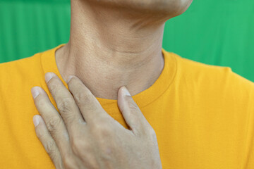 Thyroid gland inflammation at neck, goiter, throat cancer, sore throat and cough, man with neck pain on green, neck health problems concept