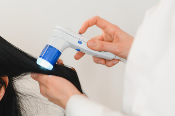A dermatologist trichologist makes a computer diagnosis of the hair condition of an attractive...