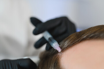 Naklejka premium Man getting hair treatment at beauty salon, having mesotherapy session. Female therapist hands in protective gloves making injection with syringe