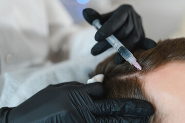 Side view of handsome man getting hair treatment at beauty salon. Man having mesotherapy session at...