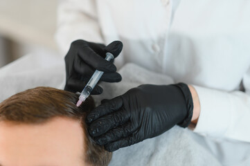 Side view of handsome man getting hair treatment at beauty salon. Man having mesotherapy session at...
