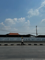 Demak-Indonesia, November 14, 2023: A street vendor balancing goods on his head, walking along a...