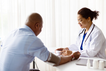 Female doctor checks patients blood pressure with care and precision using a digital monitor during...