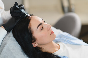 Beautiful middle woman receiving hair mesotherapy injection from competent beautician