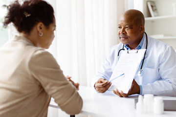 Doctor showing medical report to pregnant patient during consultation. Informative health checkup...