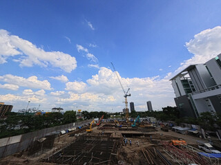 Construction workers operating heavy machinery on a building site in a dense city center