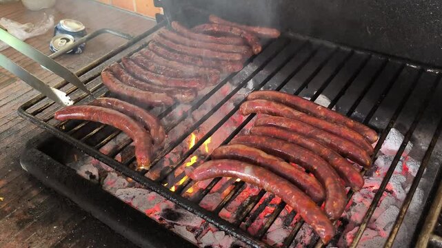 Merguez sausages and chipolatas cooking on the barbecue