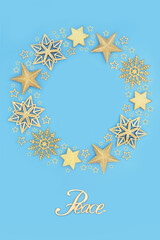 Peace on Earth sign with gold bauble Christmas wreath decoration, star and snowflake glitter ornaments on blue. Festive concept for the Xmas and New Year holiday season.