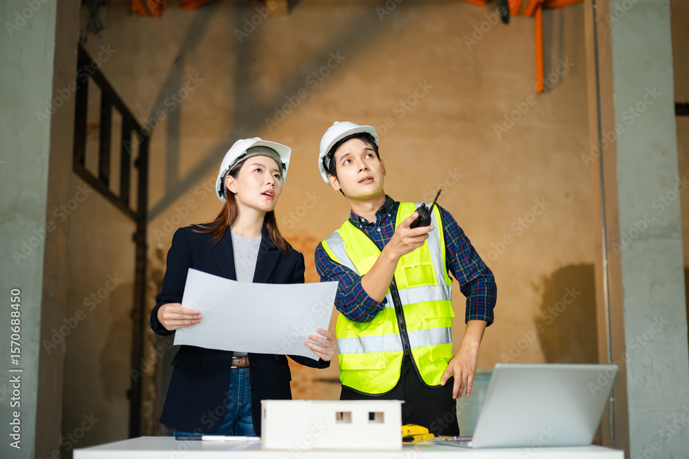 Poster construction engineer in a safety vest and an architect with a hard hat examine blueprints and a sca