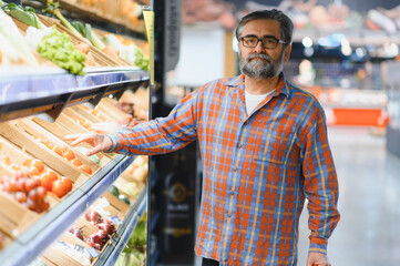 Mature senor in the vegetables section of the supermarket