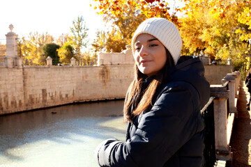 A beautiful young woman looking straight ahead on an autumn day and behind her the river.