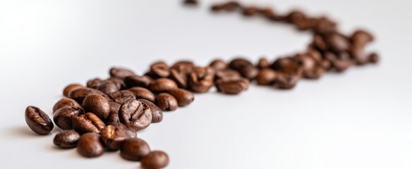 The coffee beans scattered in a creative and artistic arrangement on a white surface.
