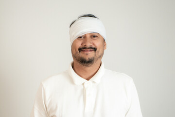 Young man with bandaged head giving thumbs up, smiling to show he’s fine after an accident.