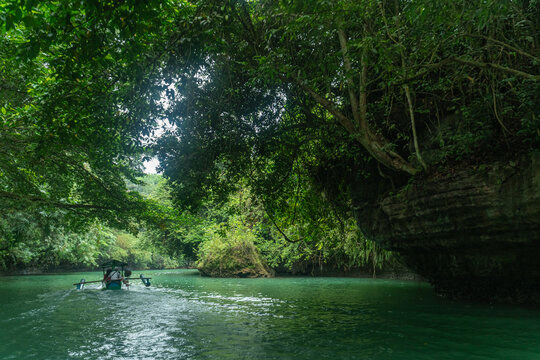 Wide shot of a boat crossing in the river of Green Canyon in Pangandaran, West Java, Indonesia. One of the most famous tourist attractions in West Java. - Powered by Adobe