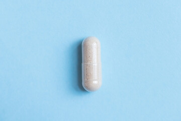 Macro capsule dose tablet on blue background. Natural vitamins or medicine layout, promoting...