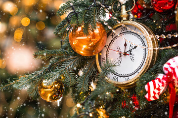 Golden retro clock on a Christmas tree. The clock hands show 12 o'clock. Beautiful background for...