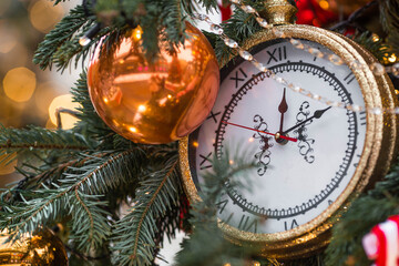 Golden retro clock on a Christmas tree. The clock hands show 12 o'clock. Beautiful background for...