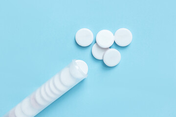 White round tablets scattered from a transparent plastic tube with a blue lid. Healthcare and...