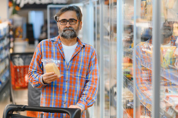 Elderly man choose cheese in supermarket