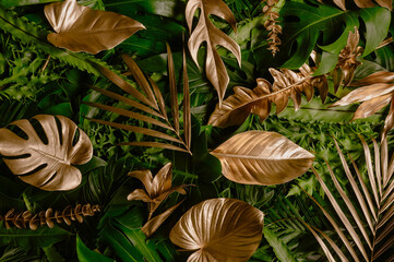 Creative nature background. Gold and green tropical Monstera and palm leaves. Minimal summer...