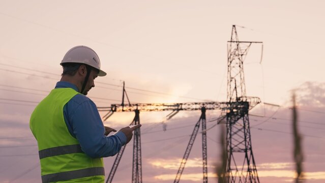 technology concept with high voltage power lines. electrical engineer helmet digital tablet sunset. power engineer power plant high voltage voltage energy. concept electrical engineer working sunset. - Powered by Adobe