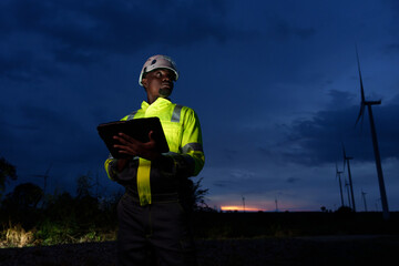 Engineers surveying the power generation at a wind farm, natural energy, industry and environment, clean energy at night
