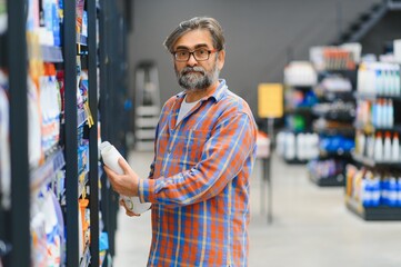 Adult man buyer chooses cleaning products in household chemicals store