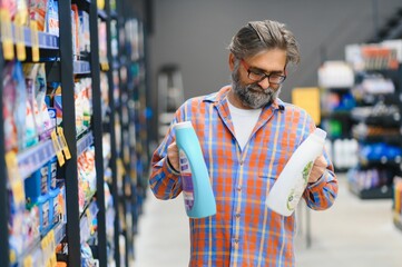 Adult man buyer chooses cleaning products in household chemicals store