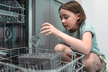 Child loads dishwasher. Everyday life concept,