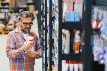 Adult man buyer chooses cleaning products in household chemicals store