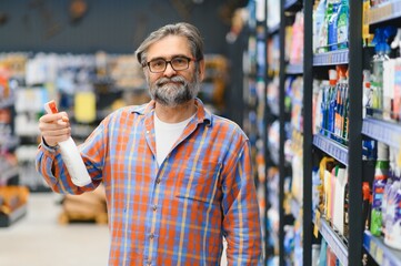 Adult man buyer chooses cleaning products in household chemicals store