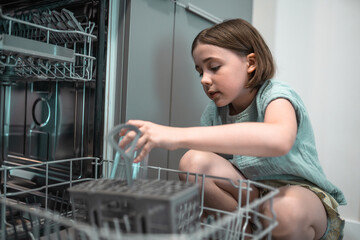 Child loads dishwasher. Everyday life concept,